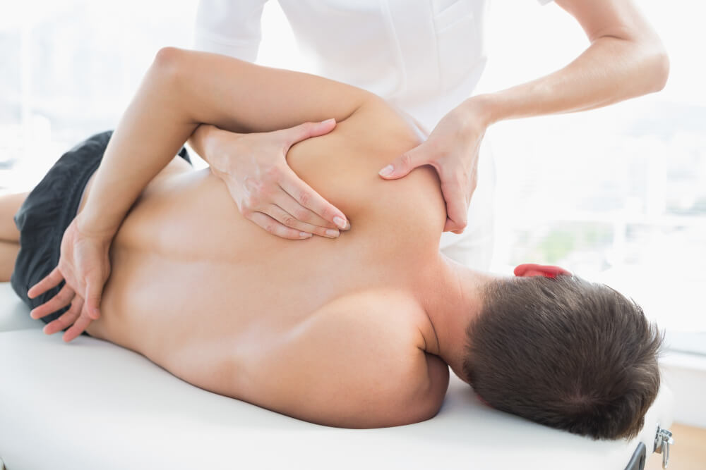 Physiotherapist giving shoulder massage to man